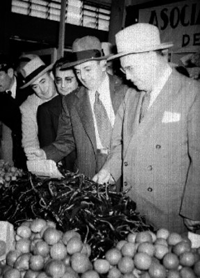 Funcionarios observando chiles en el puesto de un mercado durante su inauguración