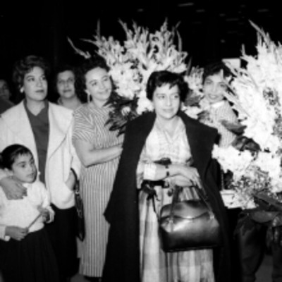 Maria Cristina Salmorán y mujeres sosteniendo flores durante su recepción en el aeropuerto, retrato de grupo