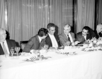 Salomón González Blanco, Julio Santos Coy y miembros del Sindicato de Radiodifusión, televisión y conexos conversando durante un banquete en un salón
