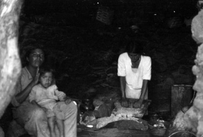 Mujer muele alimentos en metate