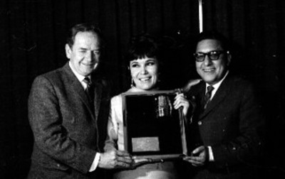 Hombnre lee reconocimiento a mujer en un banquete