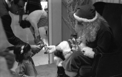 Niña recibe dulce de un hombre disfrazado de Santa Claus
