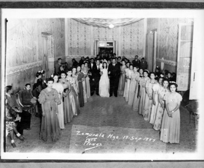 Reina de belleza desfila en un salón rodeada por sus damas de compañía