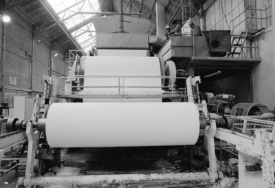 Obreros operan en máquina bobinadora de papel, fábrica San Rafael