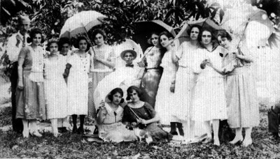 Personas reunidas en jardín portan sombrillas, retrato de grupo