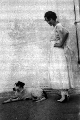 Mujer de pie con vestido largo junto a perro, retrato