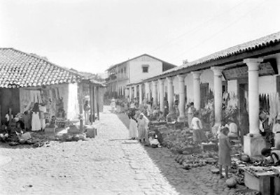Vendedores ambulantes con sus mercancías en los portales de un pueblo