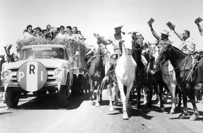 Adolfo López Mateos a bordo de camión de carga saludA a campesinos durante su campaña
