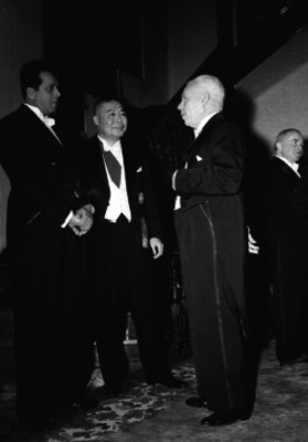Ezequiel Padilla conversando con diplomáticos al pie de unas escaleras, durante un evento sociale en un salón