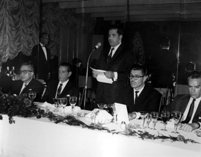 Adolfo López Mateos y comitiva escuchan discurso de funcionario durante banquete