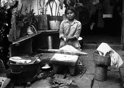 Mujer hace tortillas en un metate