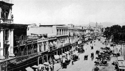 Gente y carruajes transitan en una calle del zócalo