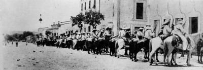 Revolucionarios a caballo frente a edificación