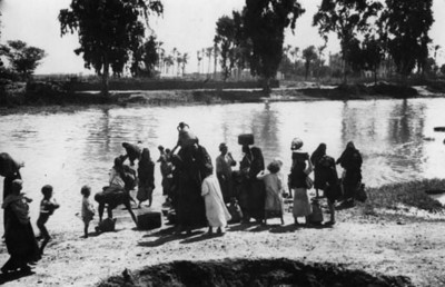 Mujeres van con recipientes por agua a un río