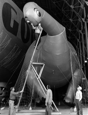 Hombres inflan globo con figura de dinosaurio