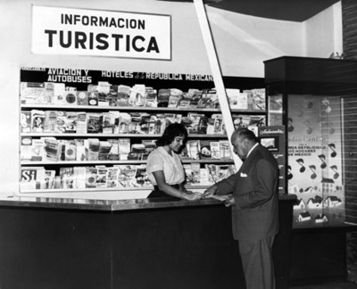 Mujer ayuda a hombre en stand de "información turística"