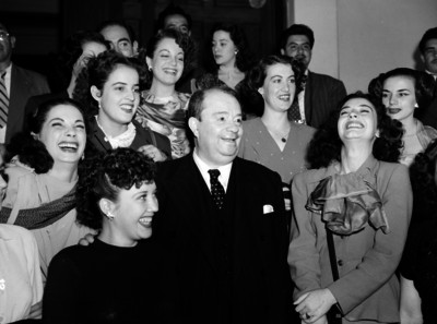 José Rubén Romero acompañado por varias mujeres, al parecer durante un evento social; en un salón