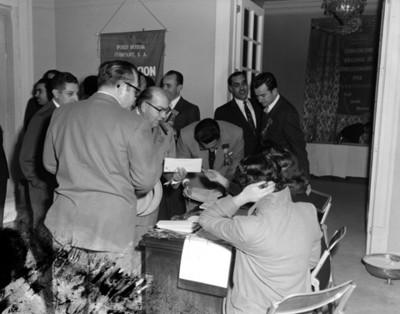 Ejecutivos reciben documentos de mujeres sentadas durante la "Convención Nacional de Concesionarios"