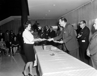 Ejecutivo entrega documento a empleada en un salón durante ceremonia