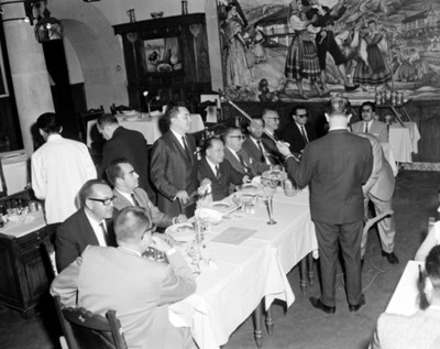 Hombres instalan micrófono ante comedor durante banquete