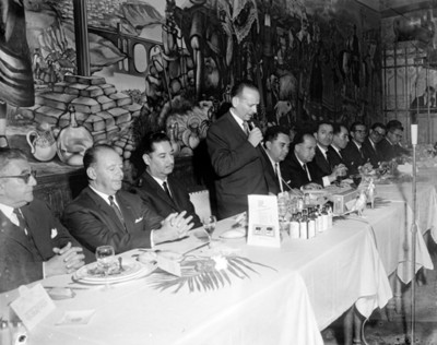 Hombre con microfono en mano pronuncia discurso durante banquete en un restaurante