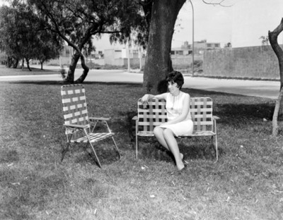 Mujer sentada en silla plegable en un parque, retrato