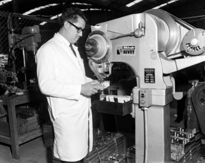 Hombre coloca radio debajo de una máquina en la fábrica Motorola