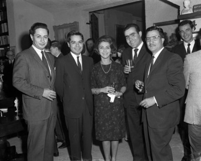 Hombres y mujer con bebidas durante reunión en la sala de una casa, retrato de grupo