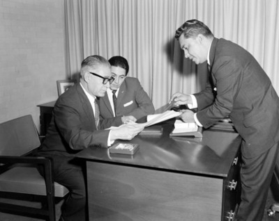 Ejecutivo muestra documento a hombres durante reunión en oficina