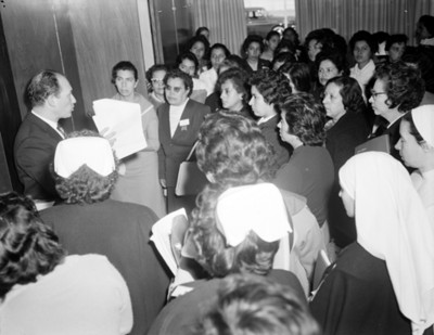 Hombre muestra documento a mujeres durante visita a empacadora