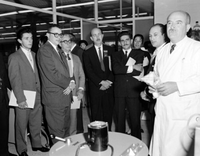 Hombres visitan laboratorio en empacadora de desyunos escolares, retrato