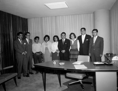 Hombres y mujeres de pie junto a escritorio de una oficina, retrato de grupo