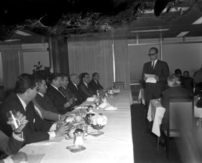 Ejecutivo lee documento ante empresarios durante reunión en restaurante
