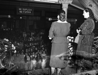 Mujeres en escaleras de una tienda departamental observan a gente