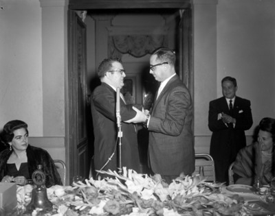 Hombres felicitándose durante acto cívico en un salón