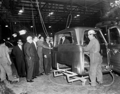 Empresarios observa un automóvil en instalación industrial