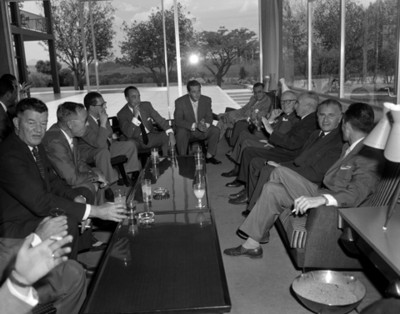 Empresarios beben y conversan sentados frente a ventanerías