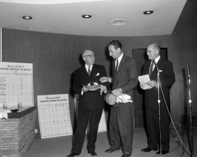 Hombres entregan reconocimiento a participante durante torneo de golf de la General Motors