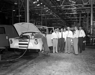 Empresarios junto a un automóvil en instalación industrial, interior