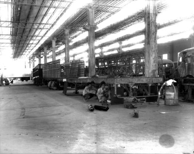 Colocan pieza automotríz a la caja de un trailer en instalación industrial