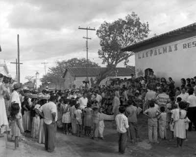 Gente observa un baile regional enfrente de restaurante las Palmas