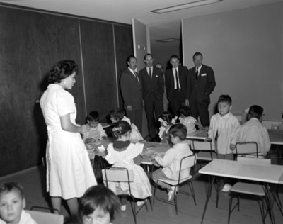 Empresarios observan a niños en el salón de un kinder