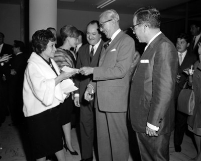 Empresario entrega documento a mujer en evento de Autos Francia, S.A.