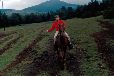 Adolescente a caballo en un pastizal, sonríe, retrato