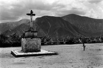 Mujer camina junto a cruz atrial, ex-convento de Los Santos Reyes