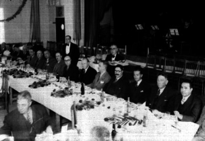 Enrique Zúñiga y varios hombres, durante un banquete en un salón de actos