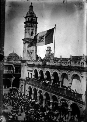 Personas presencian el izamiento de la Bandera mexicana en el Palacio municipal de Veracruz