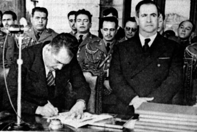 Lázaro Cárdenas firmando un documento en presencia de Manuel Ávila Camacho
