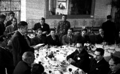 Manuel Ávila Camacho y funcionarios escuchan a un funcionario dar lectura a un documento durante un banquete