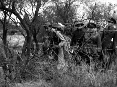 Soldados observan a través de cerca de alambre durante prácticas militares